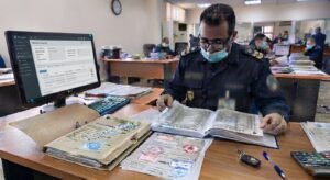 Un agent des douanes vérifie un dossier d'importation FOB et des documents papier dans un bureau de dédouanement.