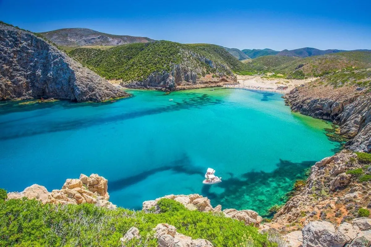 Crique aux eaux turquoise entourée de falaises rocheuses et de collines verdoyantes sur le littoral méditerranéen